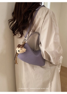 Lavender crescent moon crossbody bag styled with a beige coat and plush bear charm