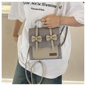 Detail of grey wool and cream leather handbag with cute bow accents and brand label