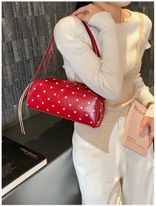 Close-up of red polka dot shoulder bag featuring a long tassel zipper on polished leather