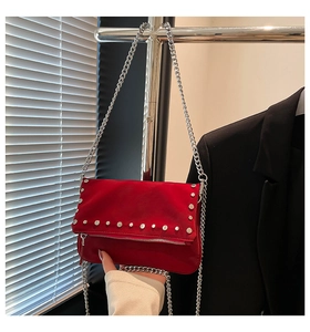 Detail of red suede shoulder bag featuring silver rivets and elegant chain strap