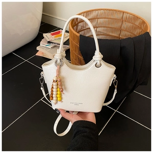 Detailed macro view of the cream bucket bag with textured leather and beaded charm
