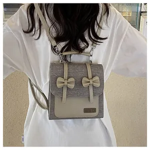 Detail of grey felt mini backpack with beige leather straps and bow accents on back