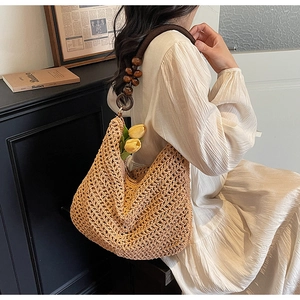 Detail of hand-woven straw tote bag featuring decorative dark wood beads and knit texture