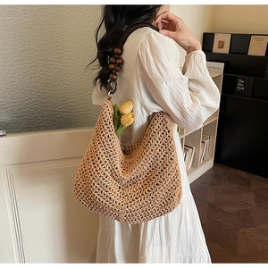 Detail of hollow knit tote bag with brown wooden bead shoulder strap on a model
