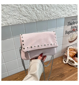 Close-up of blush pink crossbody bag featuring silver stud details and metal chain strap