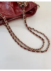 Detail of burgundy quilted leather handbag featuring a gold chain strap with a polka dot scarf
