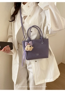 Close-up of purple bucket bag featuring COIH logo and cute plush bear charm accessory
