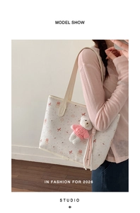 Detail of white tote bag with cute bear print and plush charm worn over the shoulder