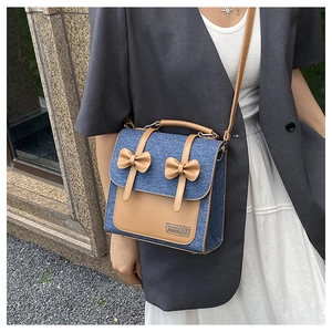 Blue denim and brown leather crossbody bag with bow detail worn by model outdoors