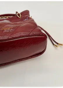 Macro view of dark red quilted leather bucket bag showing reinforced base and gold logo