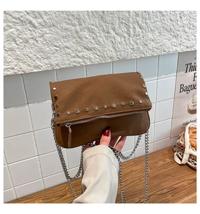 Detailed shot of brown PU leather crossbody bag with silver studs and chain strap