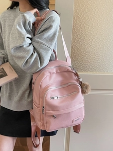 Pink faux leather backpack with multiple zip pockets and brown plush pompom charm