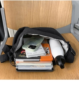 Macro shot showing large capacity of the black shoulder bag on a wooden chair