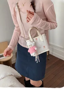 Detail of white tote bag with bear print and cute pink plush charm accessory