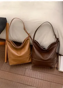 Detail of large minimalist tote bags in tan and dark brown faux leather on floor