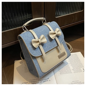 Detail showing denim and cream leather stitching with bow accent on the backpack
