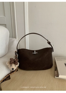 Detail of dark brown leather handbag with silver clasp and cute plush bear charm