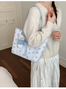 Detail of light blue floral tote bag with cartoon bear patterns and plush bear pendant