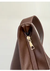 Close-up of golden metal zipper and textured brown leather on a vintage tote bag