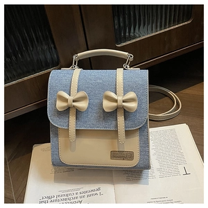 Detail of light blue denim backpack with cream leather bow and top handle on magazine