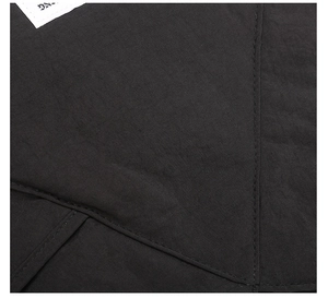 Dettaglio del tessuto nero resistente con cuciture precise ed etichetta della borsa tote