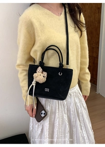 Detail of black suede tote bag with bear charm and COIH 2DN print on model