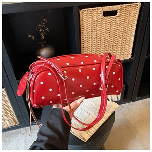 Detailed close-up of a red polka dot underarm bag featuring glossy finish and silver buckles