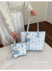 Detail of cute blue cartoon tote bags in two sizes with bear plush charms and patterns