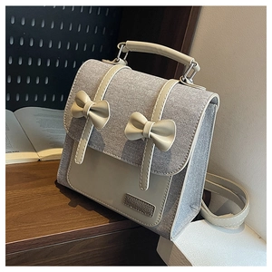 Detailed close-up of gray tweed and beige leather backpack with decorative bows