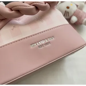 Detail of pink bucket bag featuring star embroidery and embossed logo with woven handle