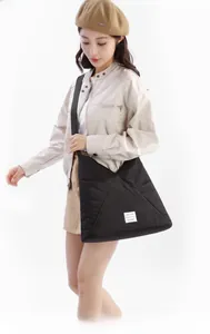 Borsa tote nera trapuntata con dettaglio etichetta bianca indossata da una modella