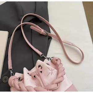 Detail of pink bucket bag featuring star embroidery and a braided top handle