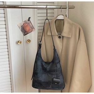 Detail of dark grey geometric patterned hobo bag with a mini pouch on metal hanger