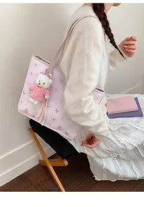 Detail of pink quilted tote bag with cute cartoon prints and a plush bear charm pendant