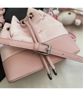Detail of pink bucket bag featuring star embroidery and adjustable leather shoulder strap