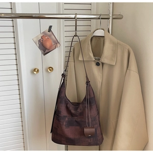 Detail of dark brown hobo bag with abstract texture and matching charm on a coat