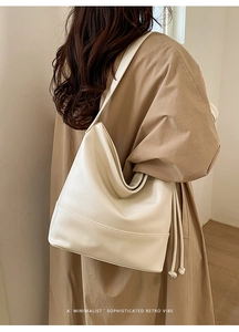 Detail of minimalist beige faux leather tote bag with subtle tassels and sleek stitching