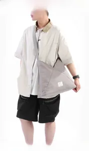 Dettaglio della borsa a tracolla in nylon grigio con cuciture geometriche e logo