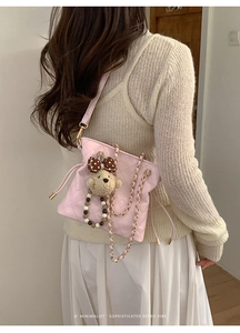 Detail of pink quilted bucket bag with chain strap and cute bear charm worn by a model