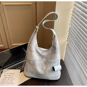 Detail of blue-grey printed hobo bag with adjustable strap and small cylinder charm