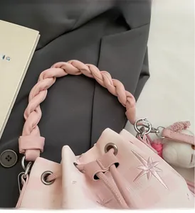 Detail of pink plaid bucket bag featuring star embroidery and braided handle with plush charm