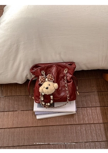 Close-up of deep red quilted leather bucket bag with golden chain and cute puppy charm