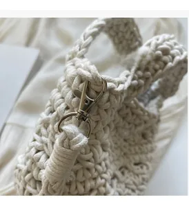 Close-up of high-shine silver metal lobster clasp on ivory hand-woven crochet bag
