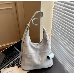 Detail of light blue hobo bag with adjustable strap and front pockets in a cozy home office