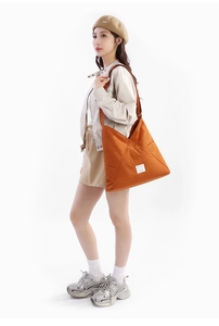Dettaglio della borsa tote in nylon pieghettato arancione con etichetta bianca cucita