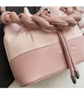 Detailed view of pink bucket bag with star embroidery and woven rope handle