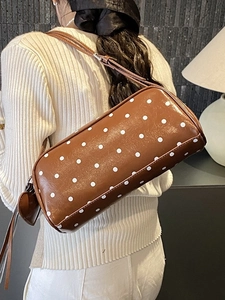 Vintage brown polka dot barrel bag with heart charm shown on model's shoulder