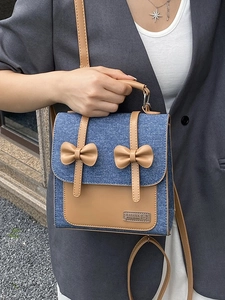 Denim and leather school style backpack with bow accents and adjustable shoulder strap
