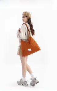 Grande borsa tote in tela arancione con struttura a triangolo indossata da modella