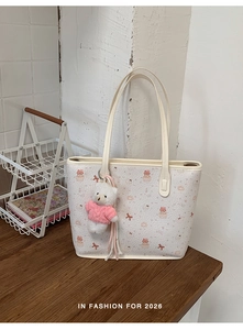 Detail of white tote bag with cute pink cartoon bears and a plush bear charm on a wood table